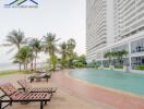 Outdoor pool area with lounge chairs by high-rise building