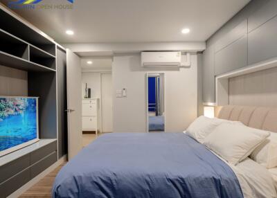 Modern bedroom with blue bedding, wall-mounted TV, and storage units