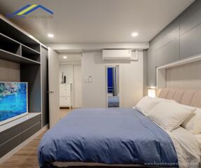 Modern bedroom with blue bedding, wall-mounted TV, and storage units