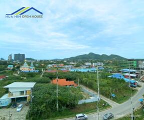 Aerial view of a residential area with houses, buildings, roads and mountains in the background.