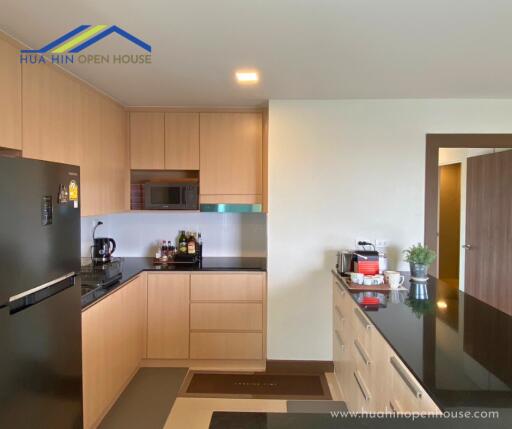 Modern kitchen with wooden cabinets, black countertop, and appliances