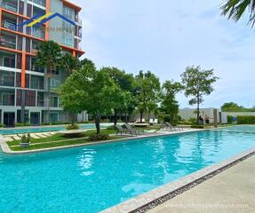 Outdoor pool area with sunbeds and trees near a residential building