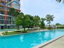 Outdoor pool area with sunbeds and trees near a residential building