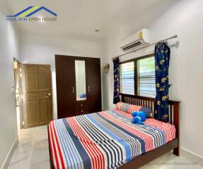 Bedroom with colorful bedspread, mirrored wardrobe, air conditioning, and window with curtains