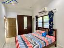 Bedroom with colorful bedspread, mirrored wardrobe, air conditioning, and window with curtains