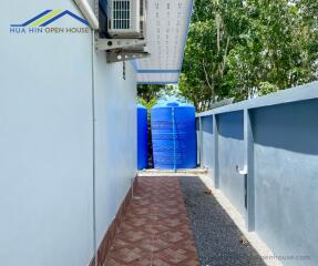 Side view of house with AC unit and water storage tanks