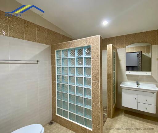 Bathroom with glass block shower and wall-mounted sink