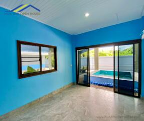 Living area with large window and glass sliding door overlooking an outdoor pool