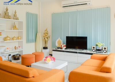 Bright and modern living room with orange sofas and decorative elements.