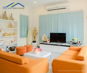 Bright and modern living room with orange sofas and decorative elements.