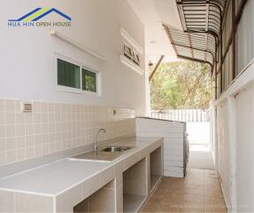 Outdoor kitchen with tiled countertops and sink at Hua Hin Open House