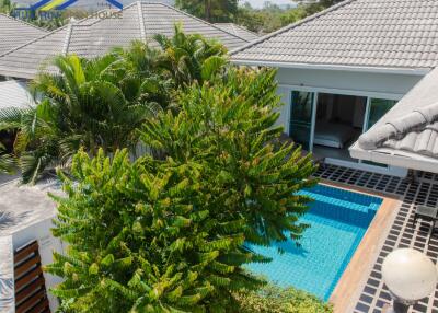 Aerial view of a modern house with a swimming pool and lush greenery.