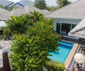 Aerial view of a modern house with a swimming pool and lush greenery.