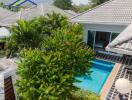 Aerial view of a modern house with a swimming pool and lush greenery.