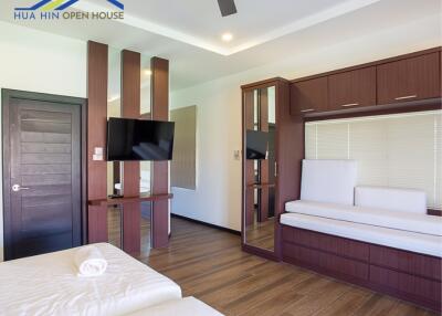 Modern bedroom with wooden floors, built-in furniture, and mounted TV