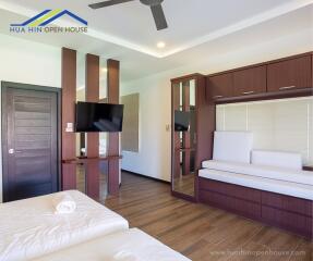 Modern bedroom with wooden floors, built-in furniture, and mounted TV