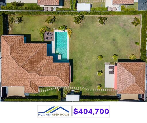 Aerial view of a property with a pool, large lawn, and two buildings