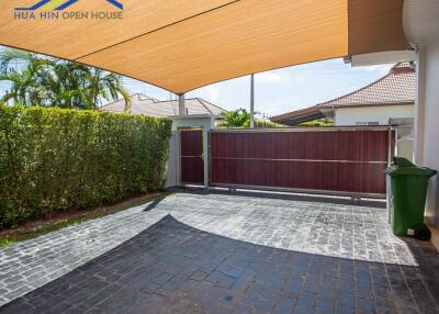 Covered carport area with tiled flooring and surrounding greenery