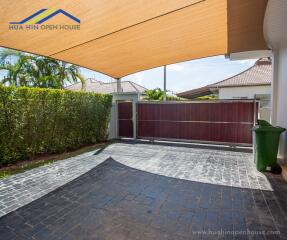 Covered carport area with tiled flooring and surrounding greenery