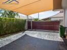 Covered carport area with tiled flooring and surrounding greenery