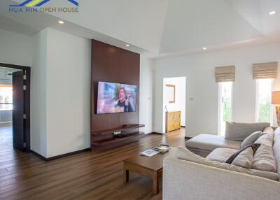 Spacious and modern living room with a wall-mounted TV and large windows