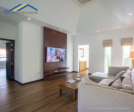 Spacious and modern living room with a wall-mounted TV and large windows