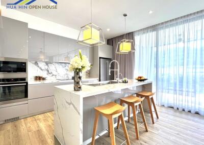 Modern kitchen with island, wooden bar stools, and pendant lighting