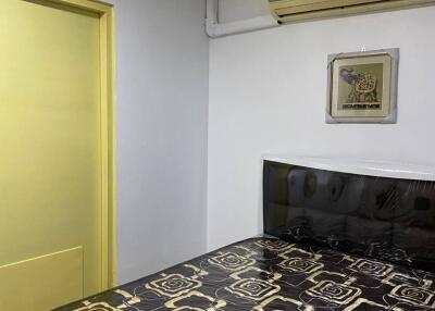 Bedroom with decorative bedspread and yellow door