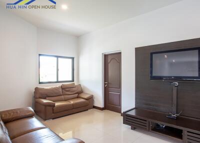 Modern living room with brown leather sofas and wall-mounted TV