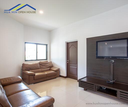 Modern living room with brown leather sofas and wall-mounted TV