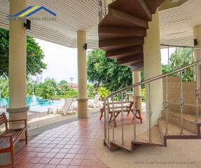 Outdoor lounge area with spiral staircase and pool view