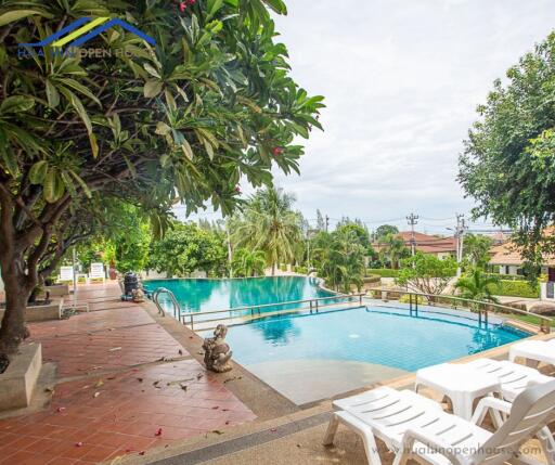 Outdoor pool with lounge chairs and surrounding greenery