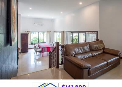 Spacious living room with brown leather sofa and adjoining dining area