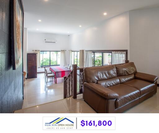 Spacious living room with brown leather sofa and adjoining dining area