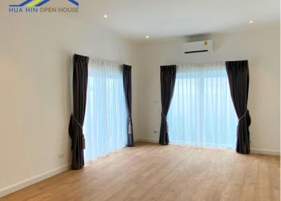 Spacious living room with wood flooring, large windows, and ceiling lights.