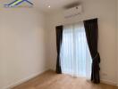 Empty bedroom with wooden flooring, curtains, and air conditioning