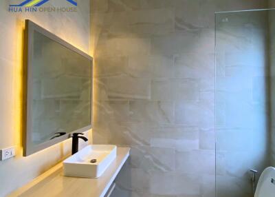 Modern bathroom with large mirror, sink, and glass shower