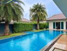 Luxury outdoor pool area with palm trees and modern house