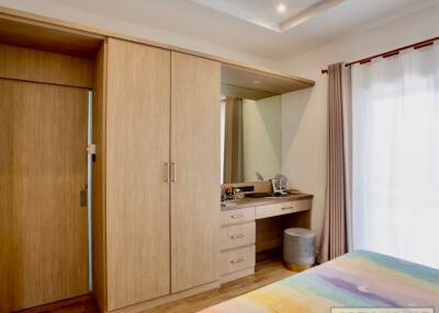 Bedroom with wooden wardrobe, vanity area, and natural lighting
