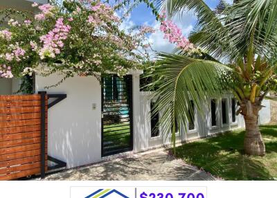 White exterior building with lush green surroundings and flowering plants