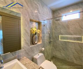 Modern bathroom with a shower, toilet, and decorative flowers.