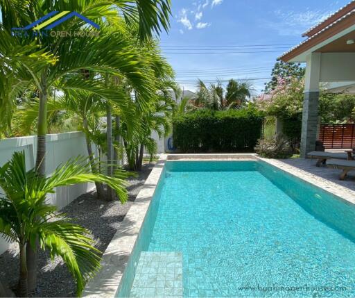 Outdoor pool area with lush greenery and seating