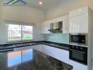 Modern kitchen with black marble countertops and white cabinets