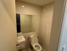 Modern bathroom with toilet, sink, and mirror