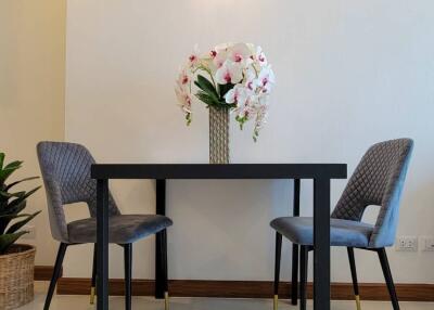 Modern dining area with a small table, two chairs, and flower vase