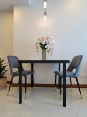 Modern dining area with a small table, two chairs, and flower vase