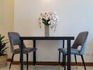 Modern dining area with a small table, two chairs, and flower vase