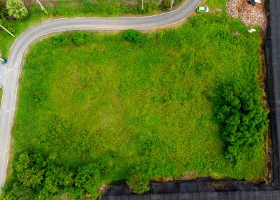 Aerial view of a green plot of land with a curved road