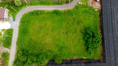 Aerial view of a green plot of land with a curved road