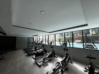 Modern fitness center with exercise equipment and pool view